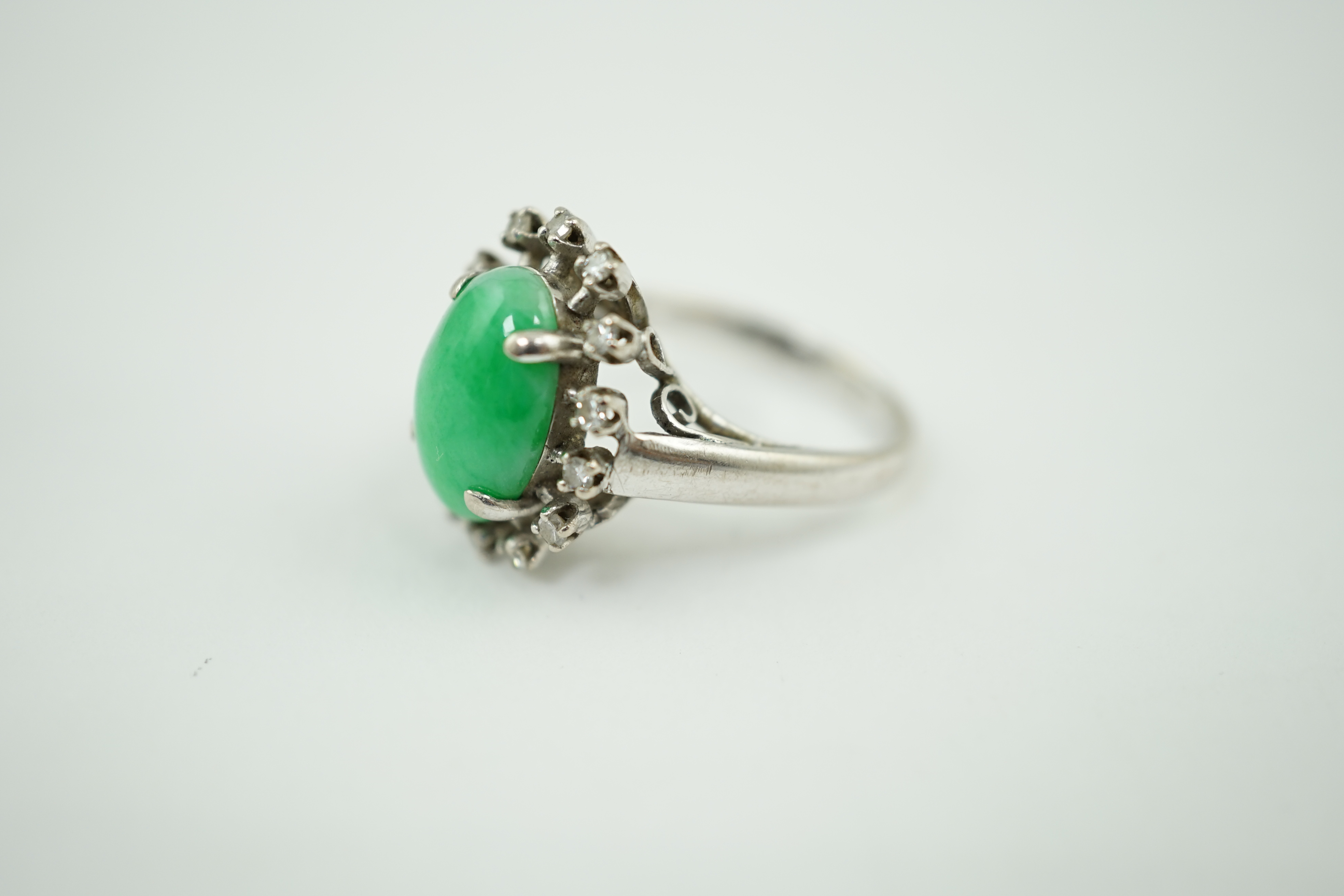 A white gold? and single stone oval cabochon jade set ring, with diamond set border